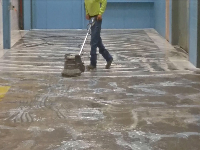 A flooring contractor prepares a concrete surface for flooring installation